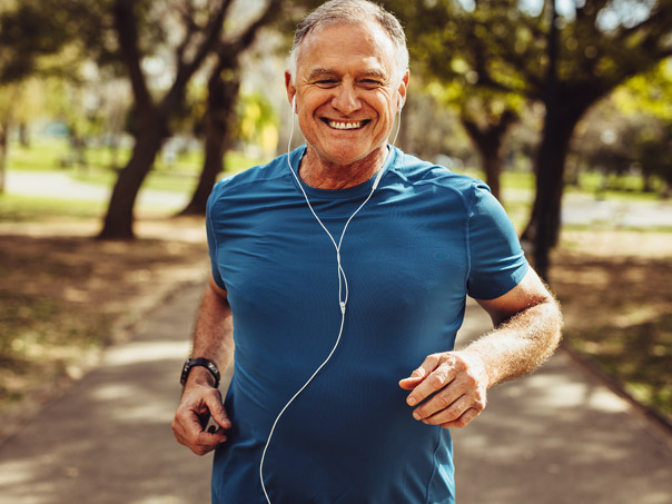 Older male running in park smiling